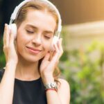 Active Listening - Woman Wearing Black Sleeveless Dress Holding White Headphone at Daytime