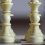 Team Objectives - Closeup of chessboard with white figures bishop and queen and row of pawns